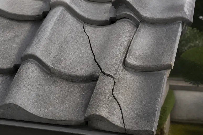 Détail d'une tuile de toiture fissurée, indice de fuite toiture forte pluie.