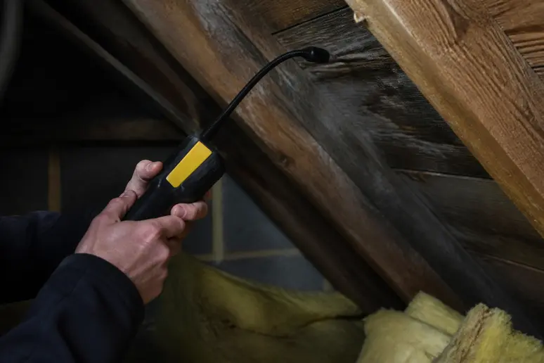 Technicien utilisant un détecteur de gaz traceur pour identifier une fuite toiture introuvable.
