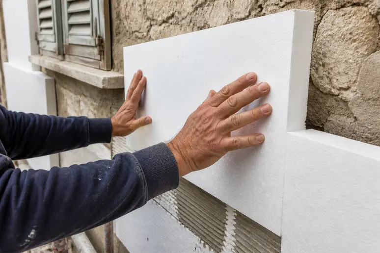Pose de panneaux isolants sur la façade extérieure d'une maison ancienne à rénover