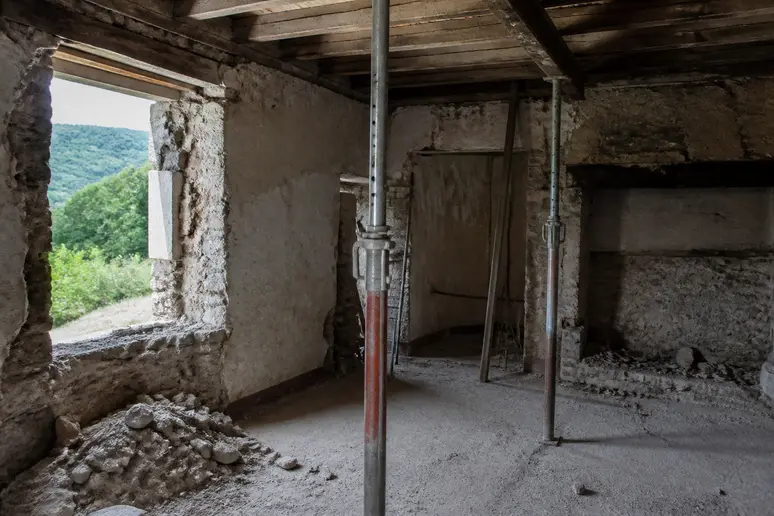 Murs en pierre et poutres apparentes lors d'une rénovation lourde de maison ancienne dans l'Aisne.