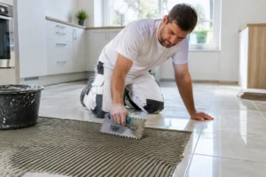 Un artisan applique de la colle pour coller carrelage sur carrelage sur un sol existant