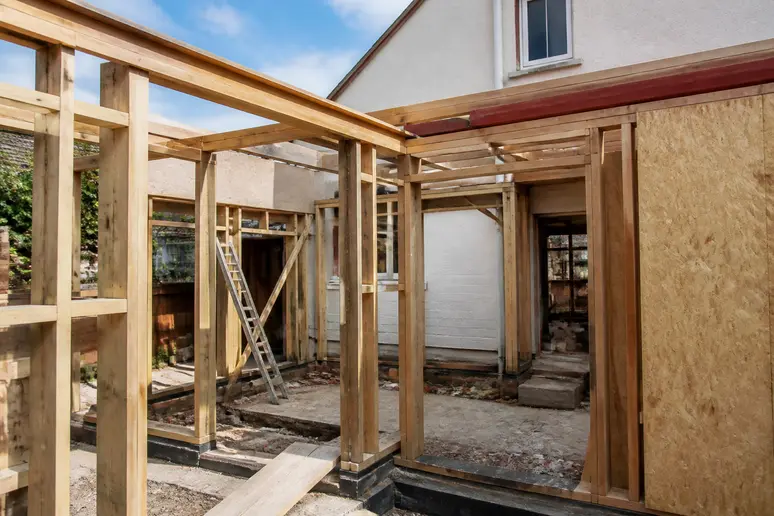 Ossature en bois d'une extension de maison en cours de construction pour calculer la surface.
