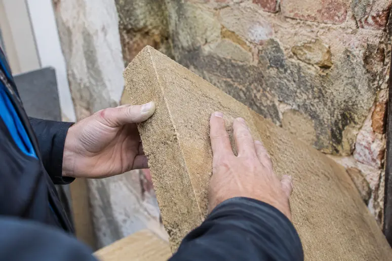 Panneau de laine de bois rigide manipulé pour isoler un mur humide de maison ancienne