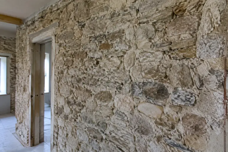 Mur ancien en pierre apparente séchant avant d'isoler un mur humide de maison ancienne
