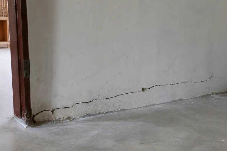 Fissure horizontale près d'un plancher sur un mur intérieur de maison fissurée