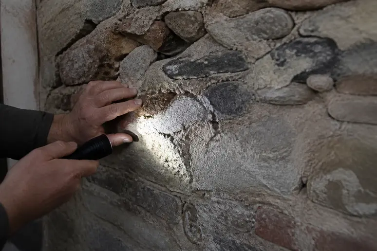 Inspection minutieuse des désordres et du salpêtre sur un mur ancien pour identifier l'humidité