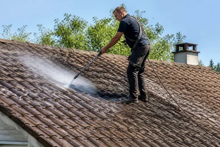 Artisan couvreur réalisant l'entretien d'une grande toiture résidentielle en pente