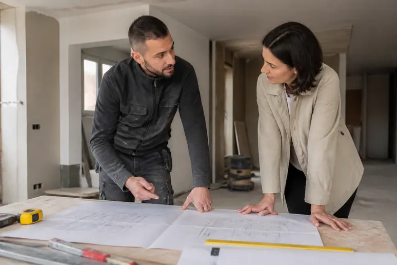 Un expert technique et un propriétaire étudient les plans d'une rénovation énergétique d'ampleur dans un appartement.