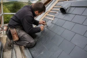 Artisan couvreur installant des ardoises naturelles sur un toit inclinable pour estimer le prix m2 ardoise toiture.