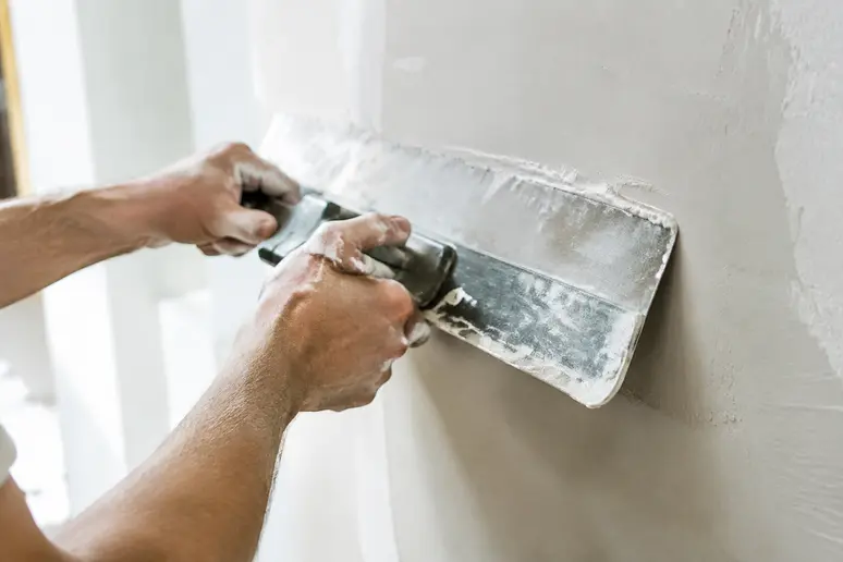 Application d'un enduit mur intérieur au couteau à enduire sur un support de chantier.