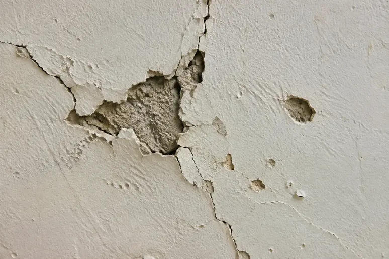 Défauts visibles sur un mur intérieur abîmé avant l'application des travaux d'enduit.